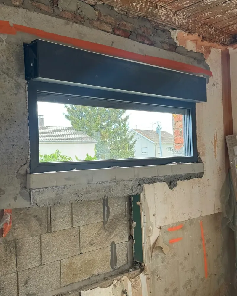 Pendant les travaux : une fenêtre anthracite et son coffre de volet roulant, dans le mur en rénovation — photo de chantier